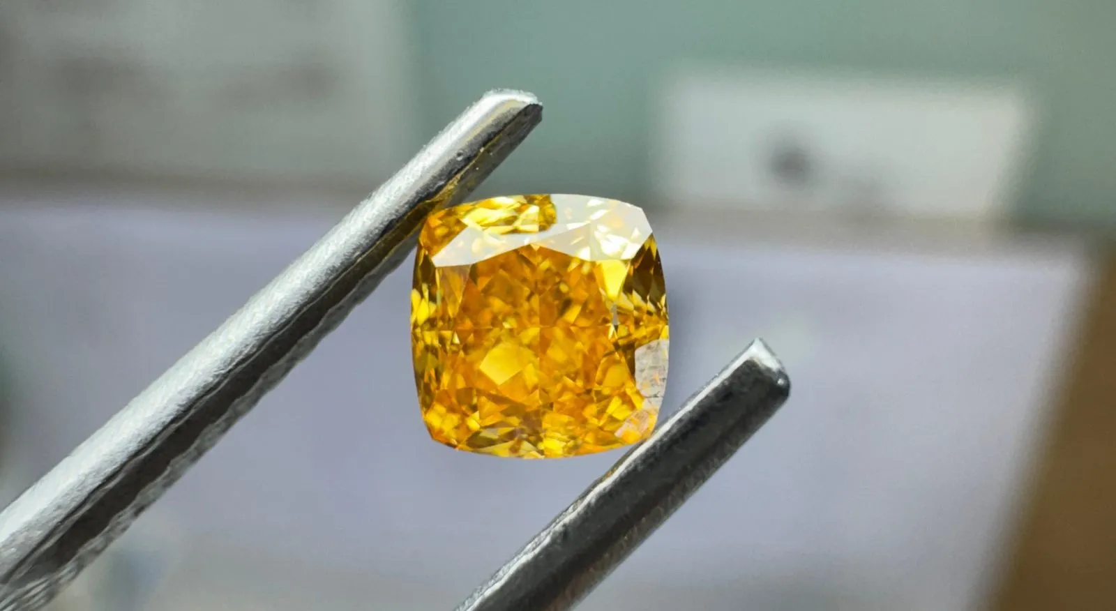 Orangefarbener Diamant in der Pinzette